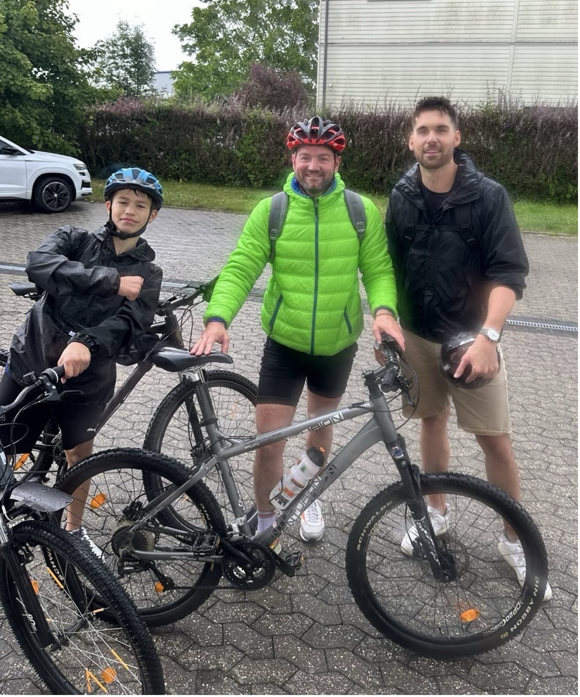 Drei Personen mit Mountainbikes nach einer Regenetappe